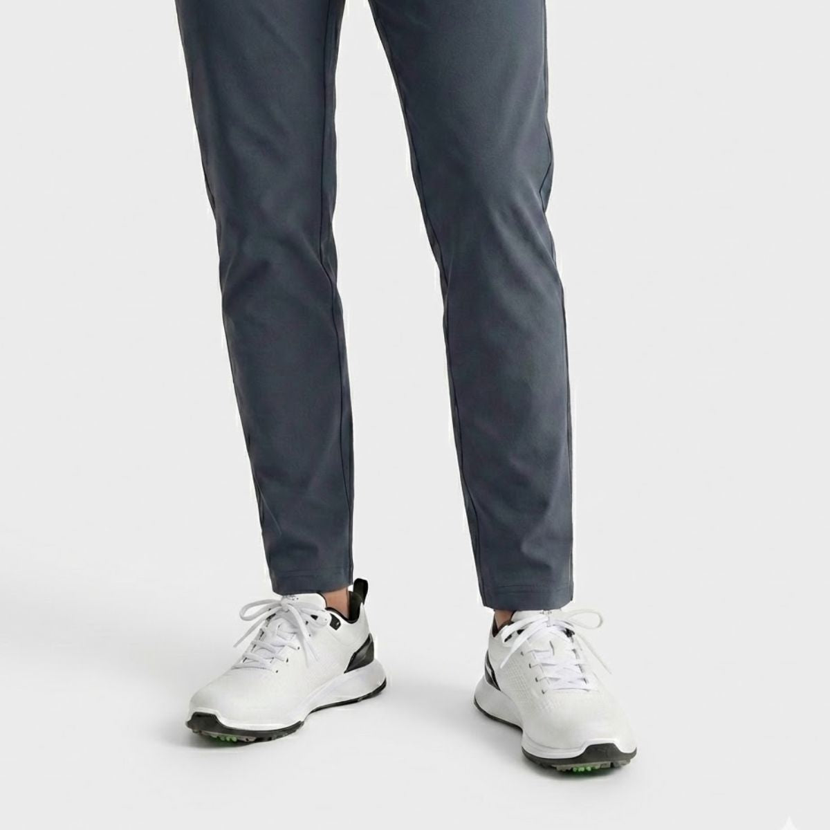 Person wearing dark gray pants and white Puma Grip Fusion-Flex golf shoes with white replacement laces.